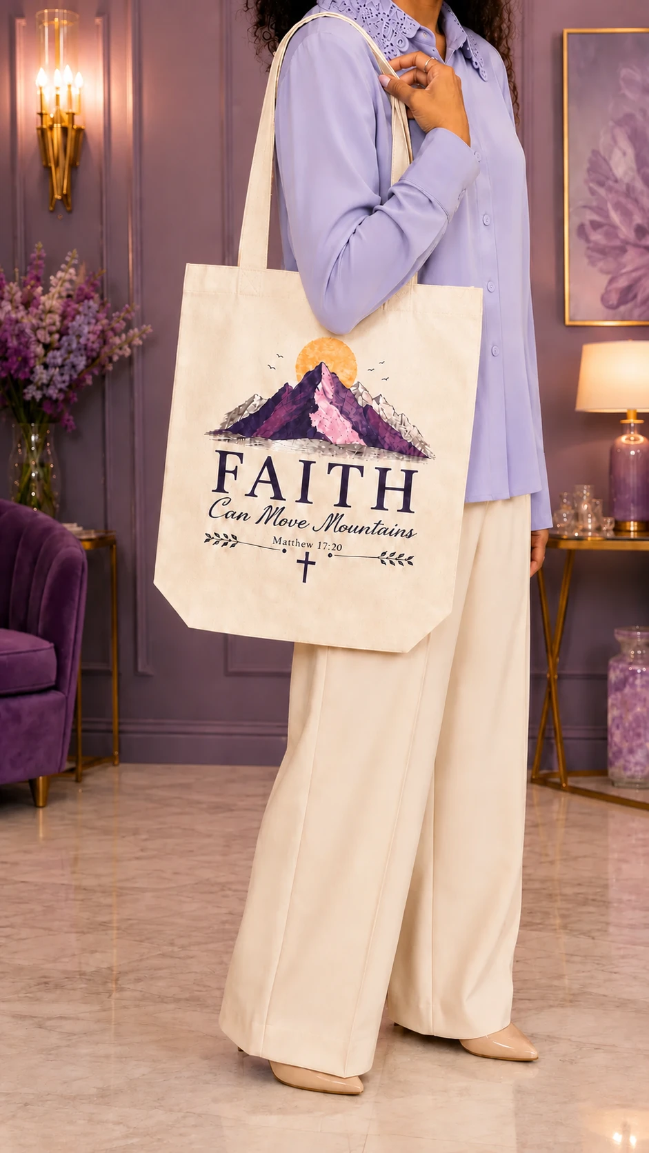 Person carrying a cream Faith Can Move Mountains tote printed with purple mountains and Matthew 17:20.